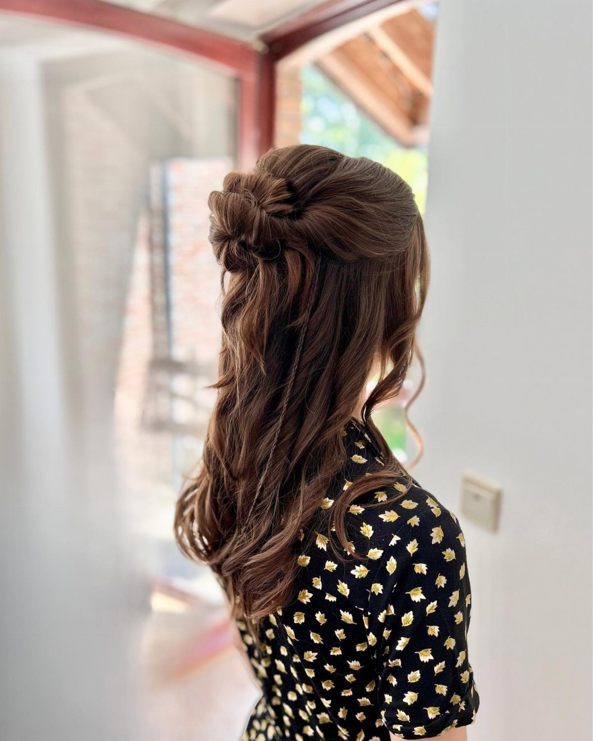 11 Half Up Half Down Wedding Hair Styles You'll Love 7 Woman with brown hair in a half-up chignon with cascading curls down her back.