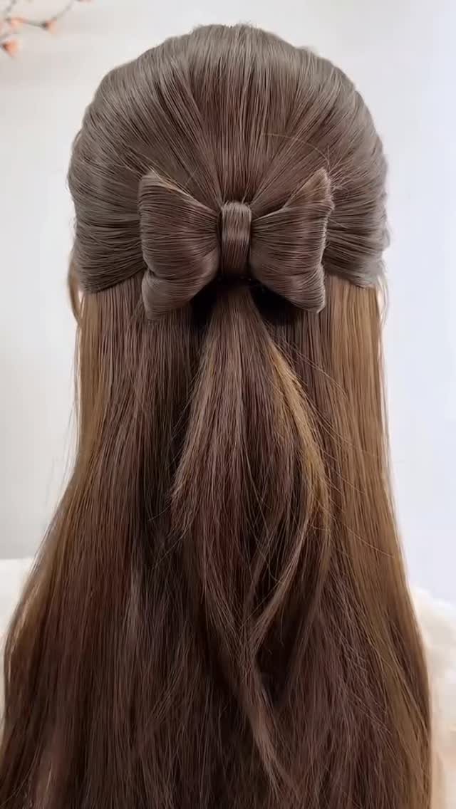 11 Half Up Half Down Wedding Hair Styles You'll Love 6 Brown hair styled in a half-updo with a large bow made of hair.