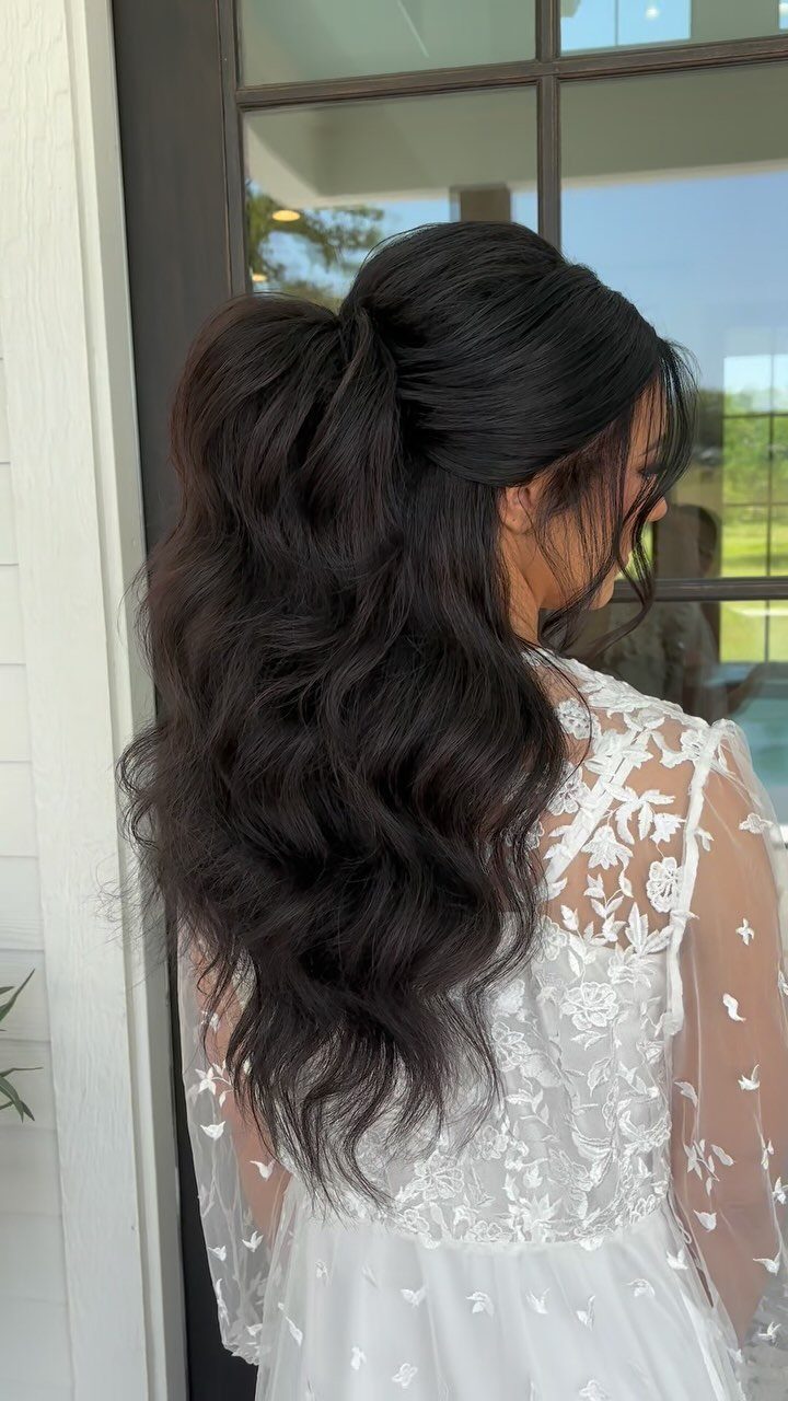 11 Half Up Half Down Wedding Hair Styles You'll Love 4 Woman with dark wavy hair in a half-up ponytail wearing a white lace dress.