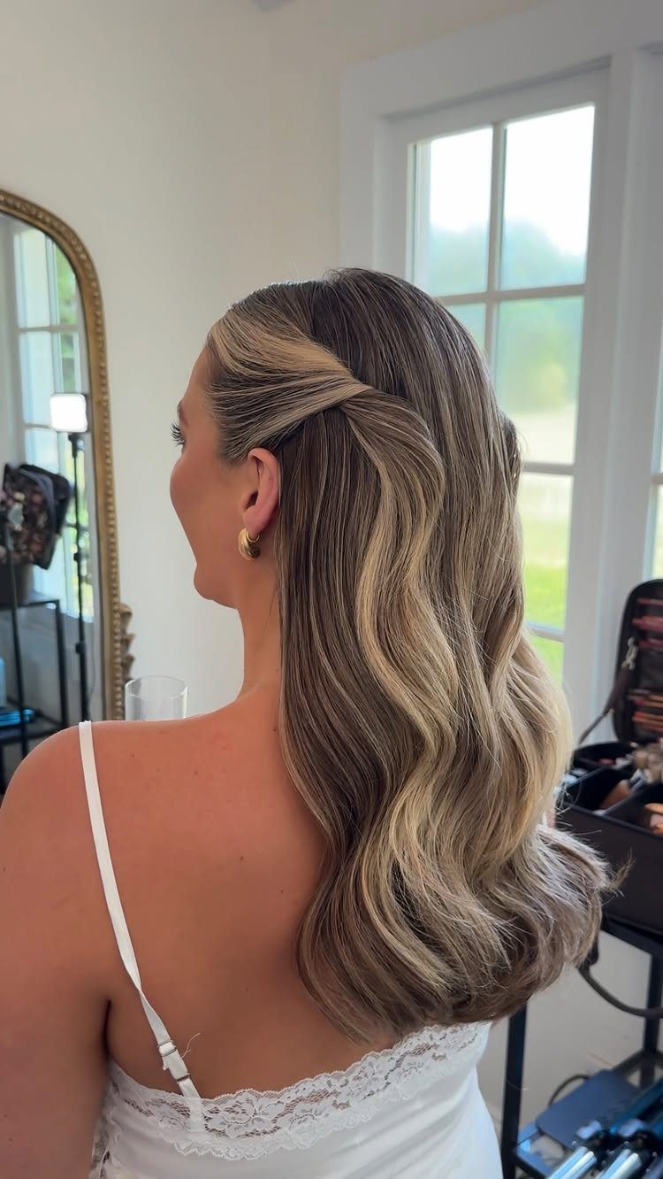 11 Half Up Half Down Wedding Hair Styles You'll Love 3 Woman with blonde highlighted hair in a half-up style with soft cascading waves.