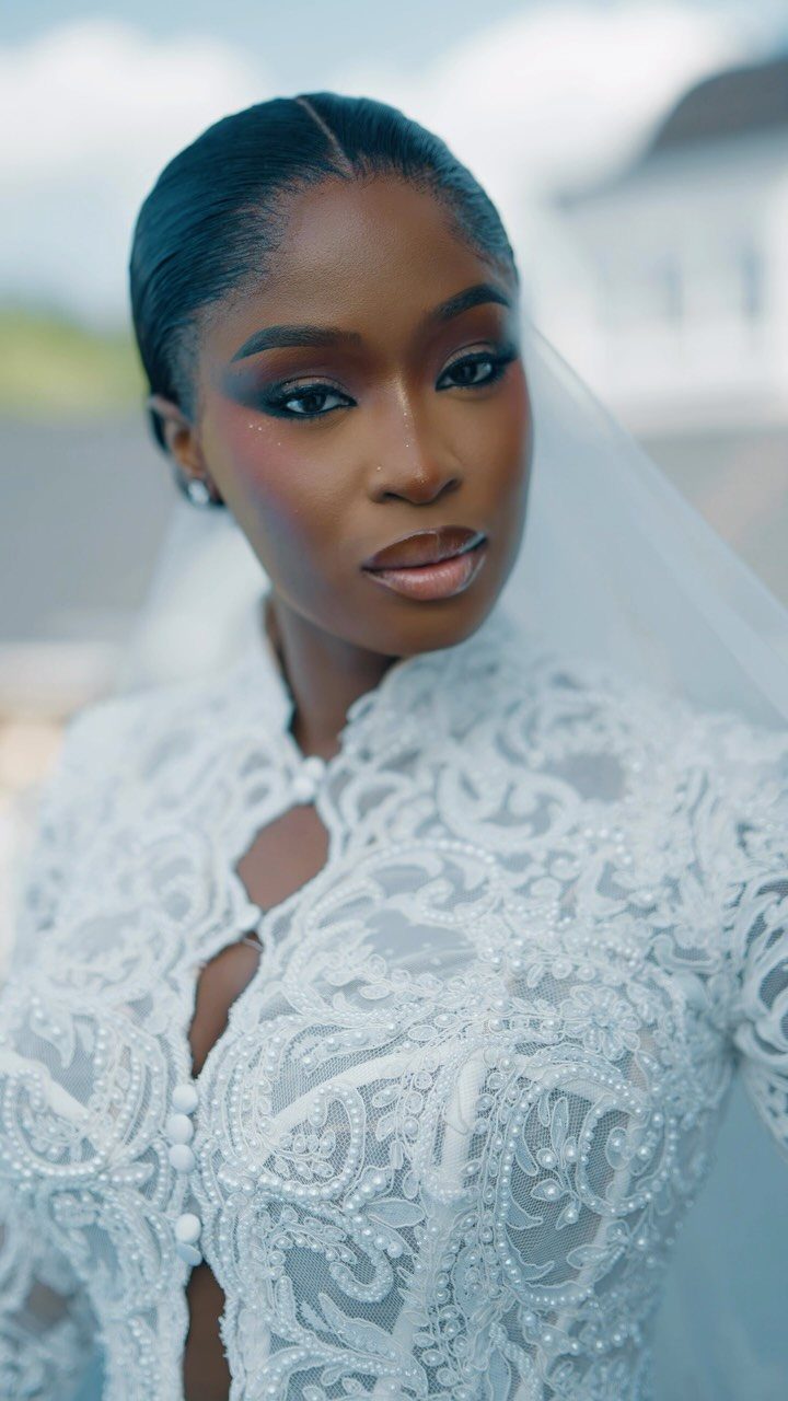 Bride in a white lace wedding dress and veil posing for a portrait