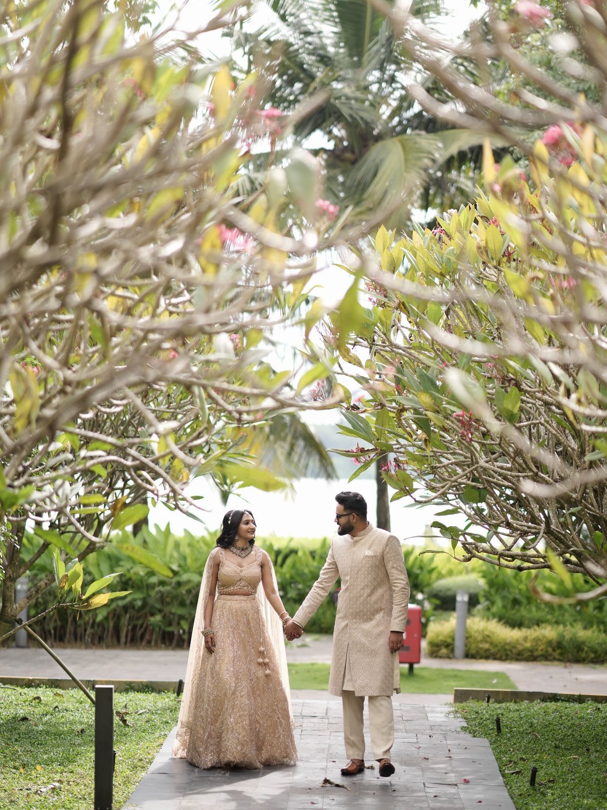 Bride and groom walking hand in hand on a path through a garden