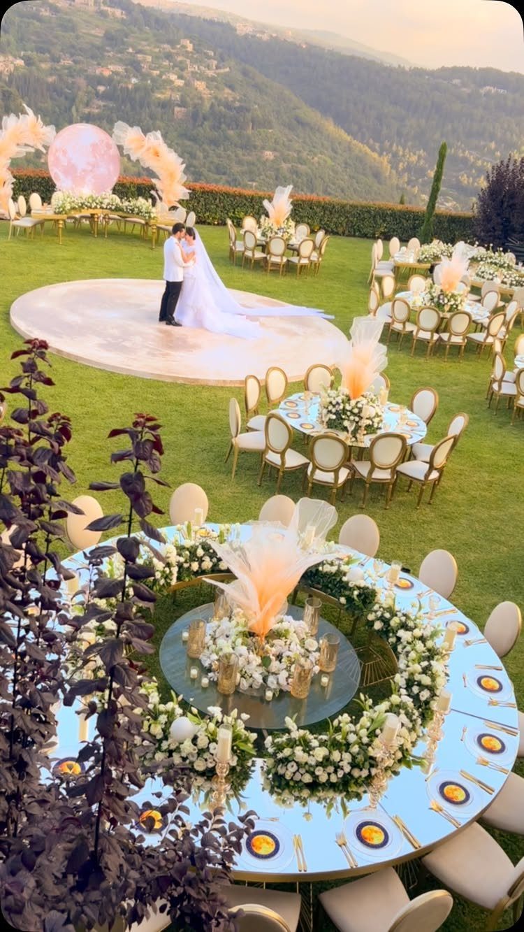 Bride and groom on a circular platform at an outdoor wedding venue with mountains.