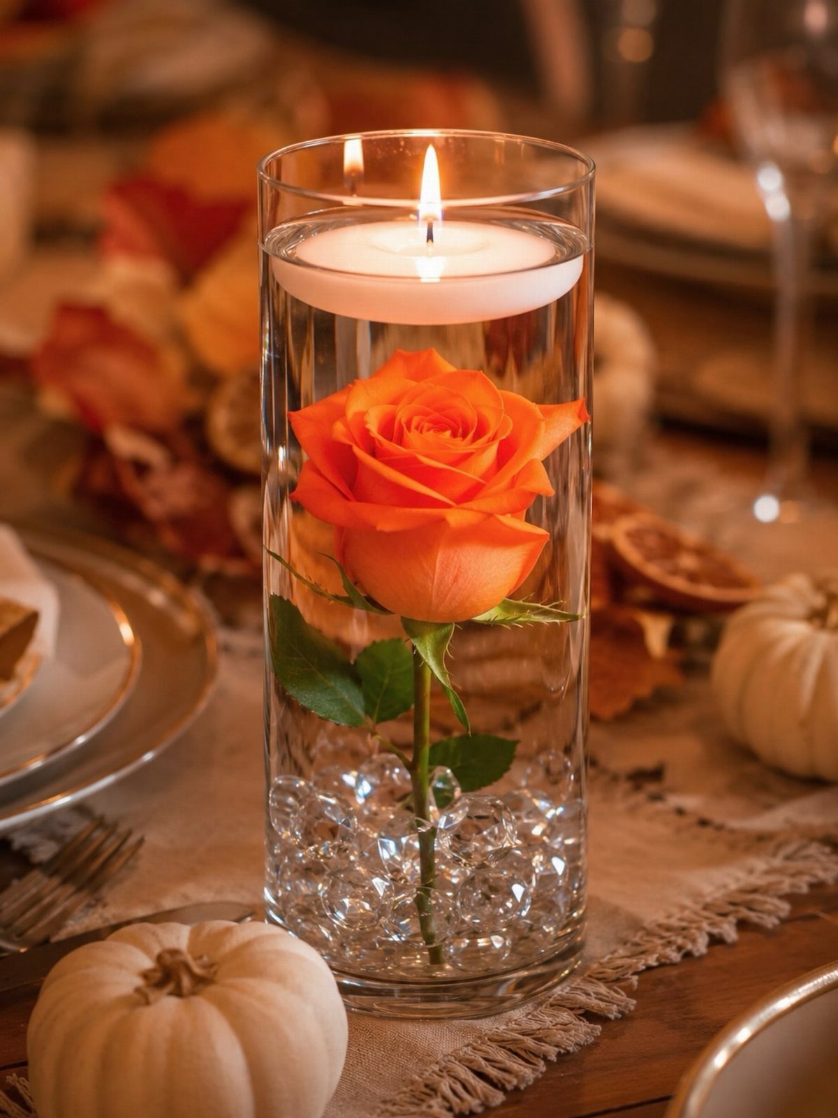 14 Candle Table Decor Ideas for Centerpieces That Feel Considered 12 A single orange rose inside a glass cylinder vase with a floating candle on top.