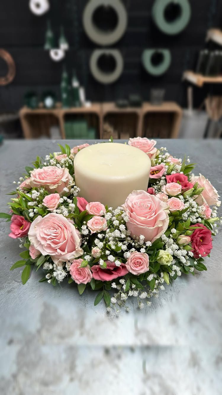 14 Candle Table Decor Ideas for Centerpieces That Feel Considered 11 A white pillar candle surrounded by pink roses and white baby's breath flowers.