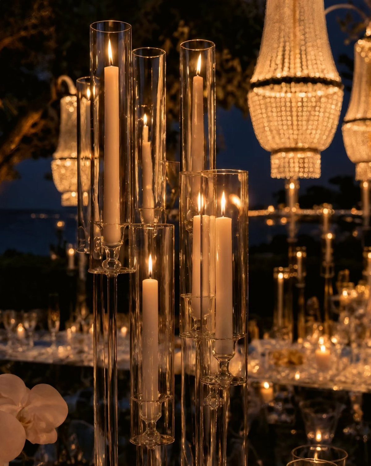 14 Candle Table Decor Ideas for Centerpieces That Feel Considered 15 Tall glass hurricane candle holders with lit white tapers on a reflective surface.