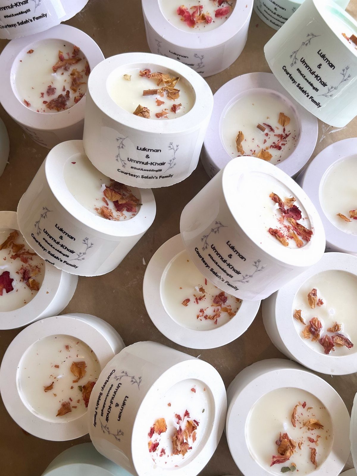 9 Candle Wedding Favors: From Beach Gel to Flower-Topped Votives 4 Numerous small white candles decorated with dried flower petals scattered on a light surface.