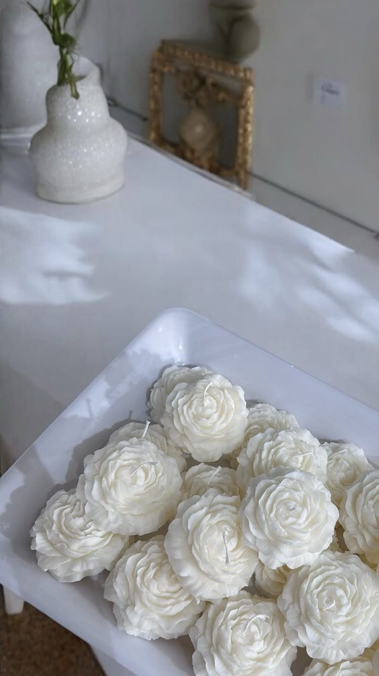 9 Candle Wedding Favors: From Beach Gel to Flower-Topped Votives 9 White rose-shaped candles arranged in a white tray on a table.