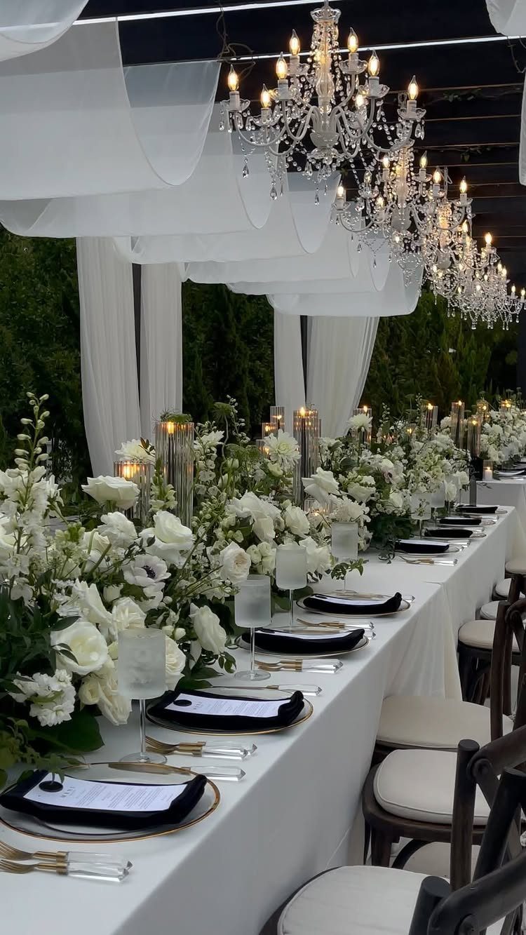 21 Color Combinations for Wedding Palettes in 2026 16 Elegant wedding reception table featuring white floral arrangements, black napkins, and crystal chandeliers hanging above.