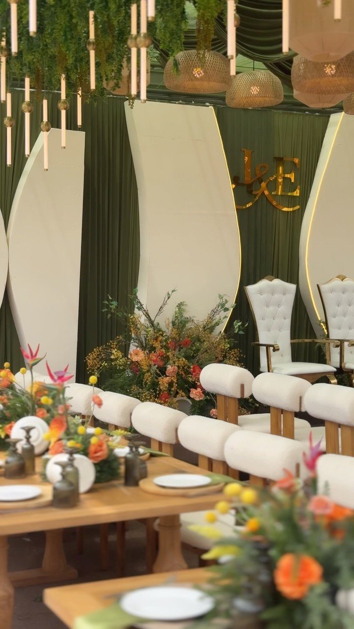 21 Color Combinations for Wedding Palettes in 2026 10 Wedding reception tables with orange floral arrangements and white chairs against green drapery.