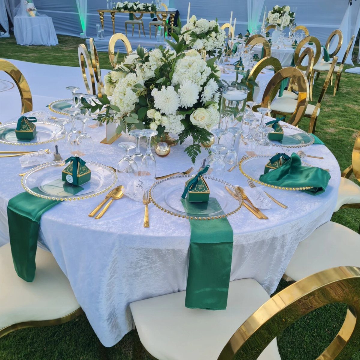 21 Color Combinations for Wedding Palettes in 2026 21 A wedding table decorated with white floral centerpieces, green napkins, and gold-rimmed plates on a white cloth.