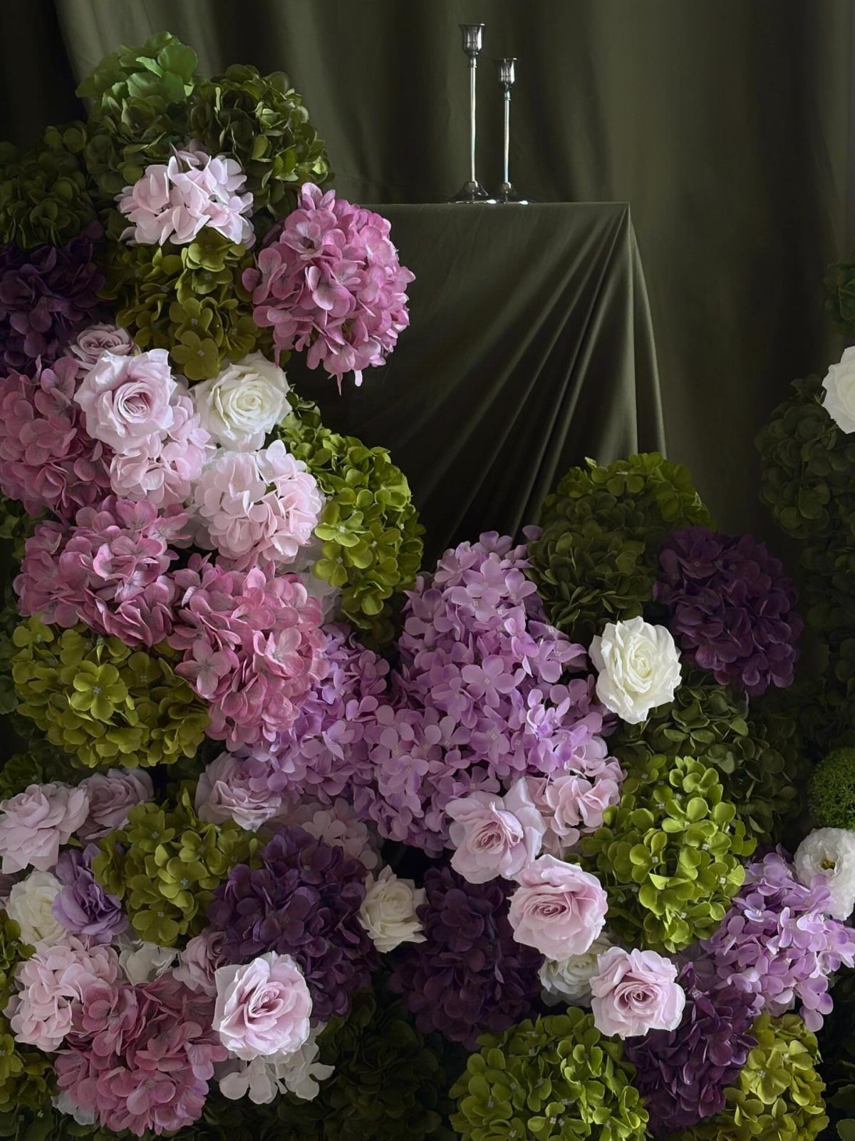 21 Color Combinations for Wedding Palettes in 2026 6 Lavender, pink, and white flowers arranged with green hydrangeas against a dark green backdrop.