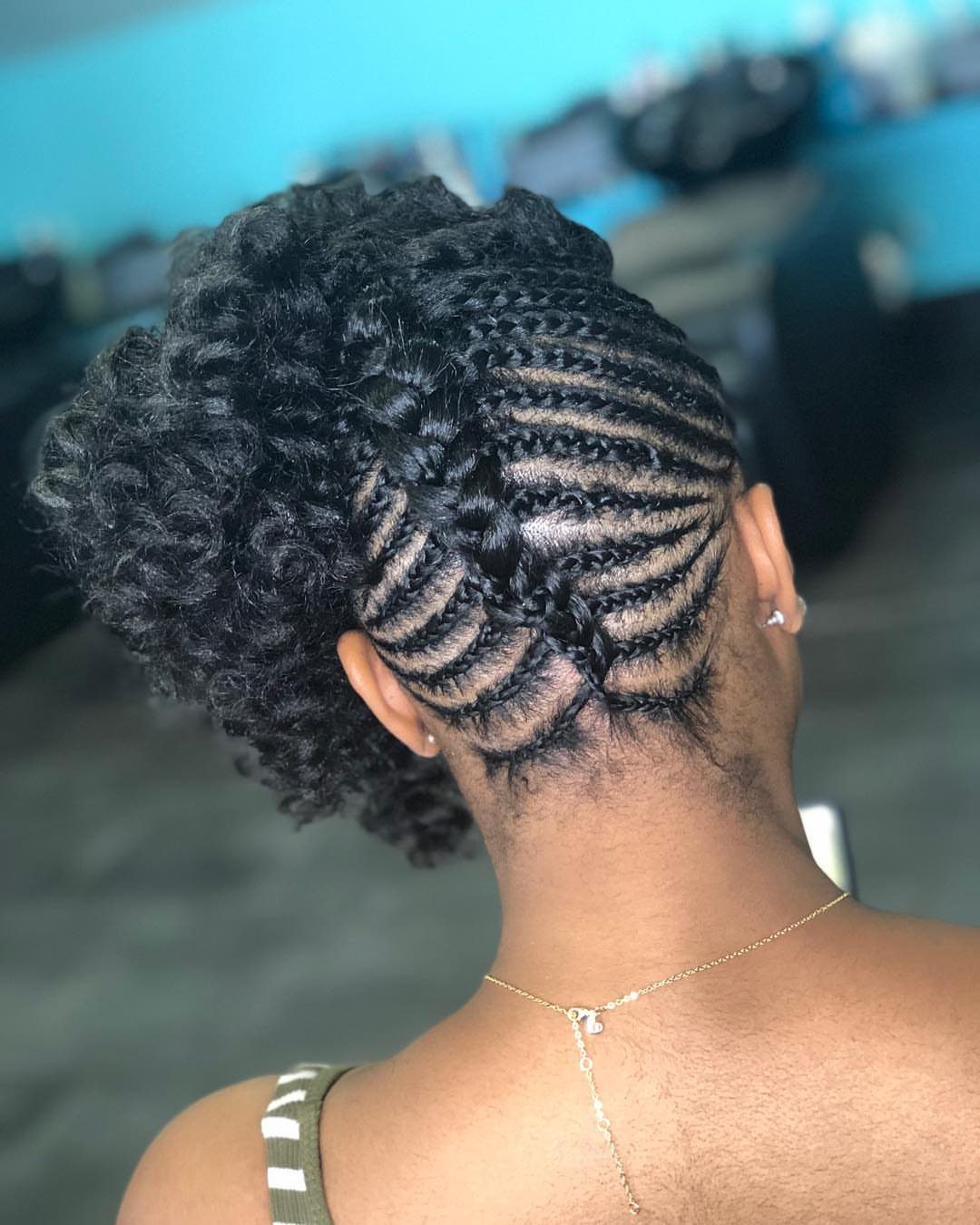 Intricate cornrow braids leading into a voluminous curly updo on dark hair.