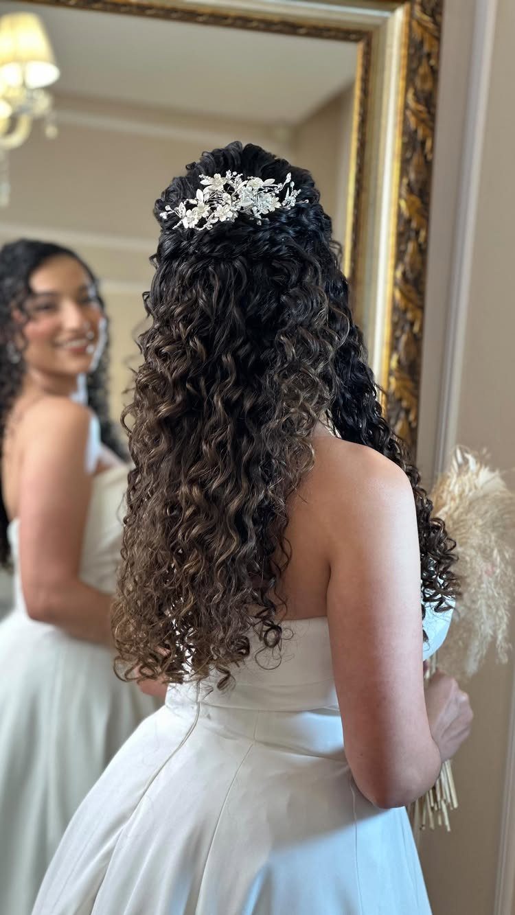 Woman with long curly hair in a wedding dress and silver hair accessory.