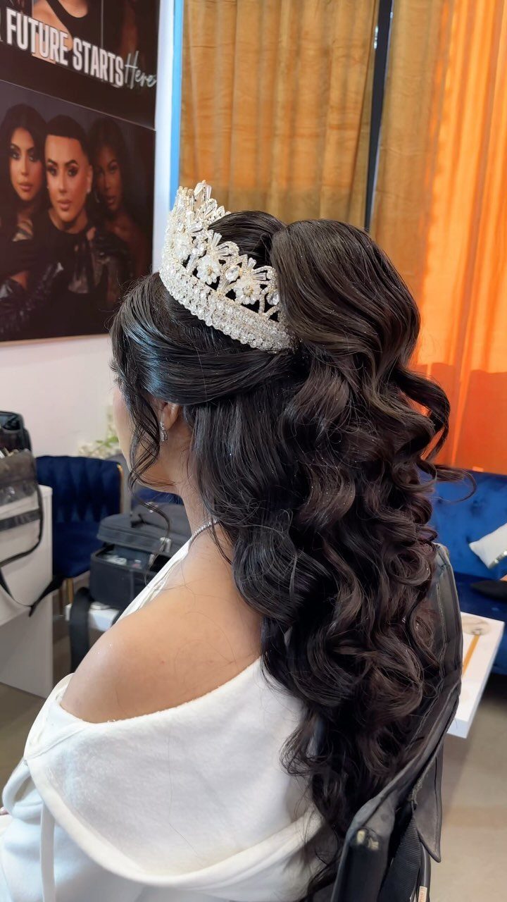 Woman with long dark curly hair wearing a sparkling silver tiara in a salon.