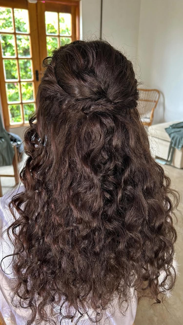 Long dark brown curly hair styled in a half-up half-down wedding look.
