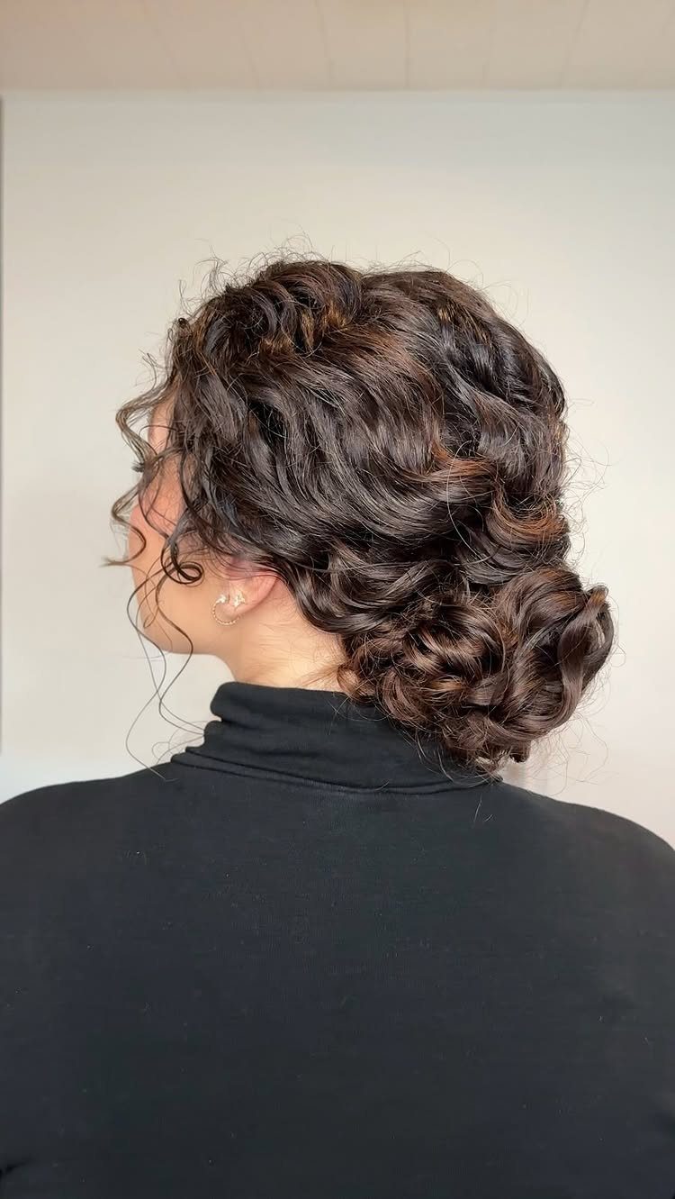 Woman with dark brown curly hair styled in an elegant low bun.