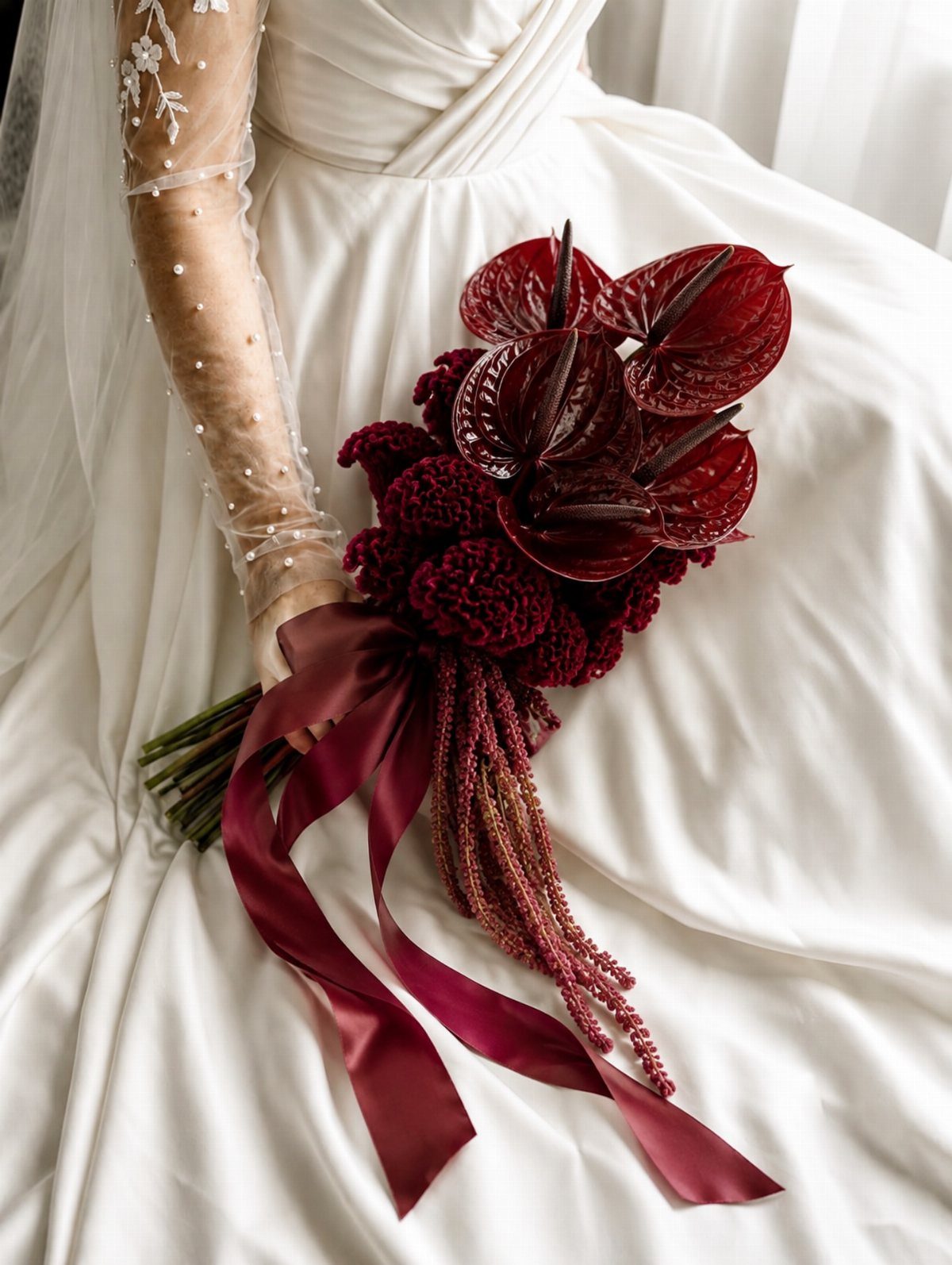 12 Dark Red Wedding Theme Ideas With Floral, Cake and Gown Picks 11 A bride in a white dress holding a dark burgundy floral bouquet with long satin ribbons.