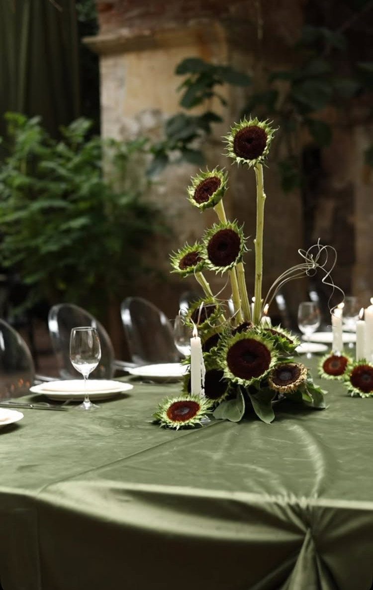 12 Dark Red Wedding Theme Ideas With Floral, Cake and Gown Picks 5 Dark red sunflowers arranged as a centerpiece on a green tablecloth with candles.