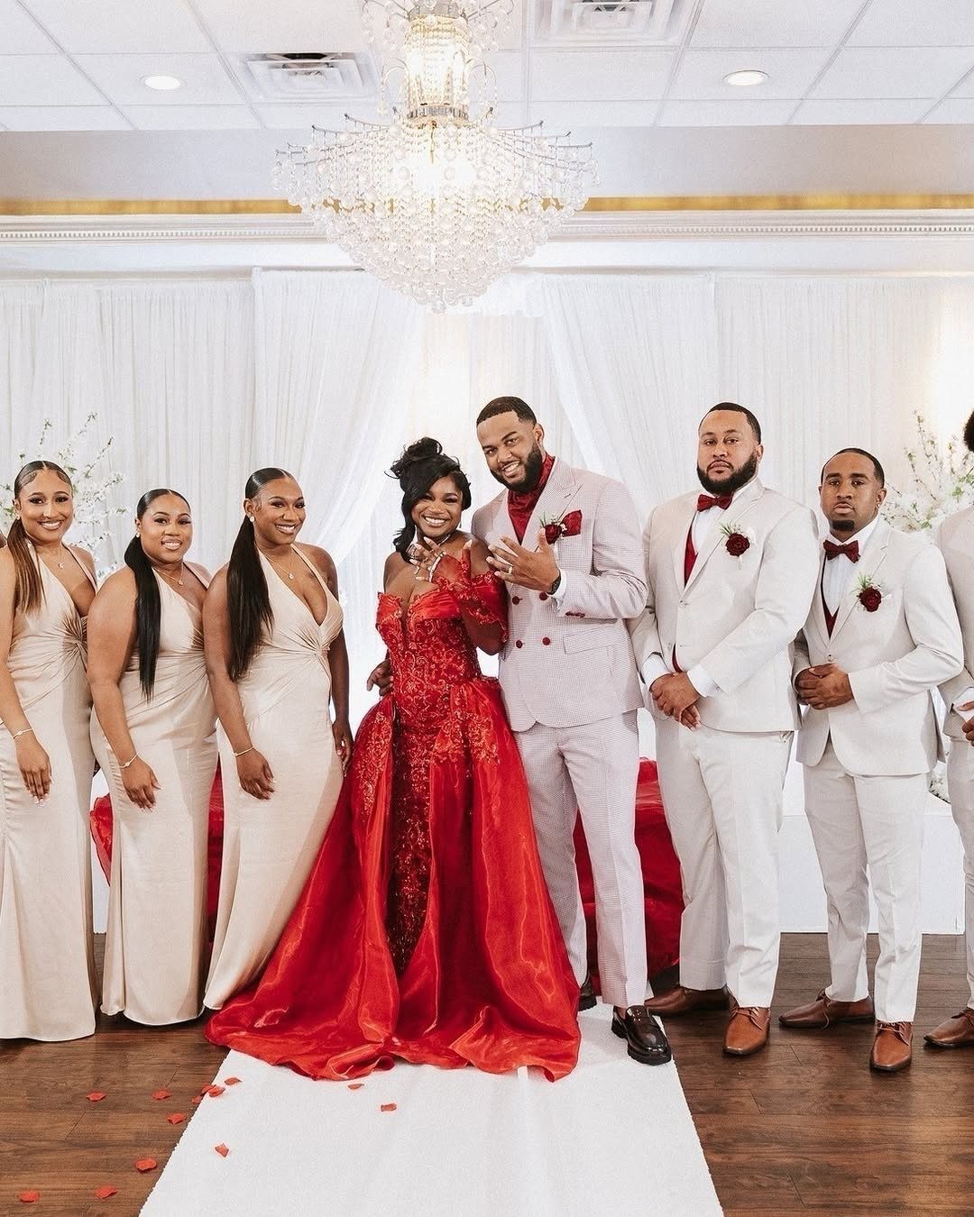 12 Dark Red Wedding Theme Ideas With Floral, Cake and Gown Picks 12 A wedding party posing together with the bride in a large red gown and groom in white.