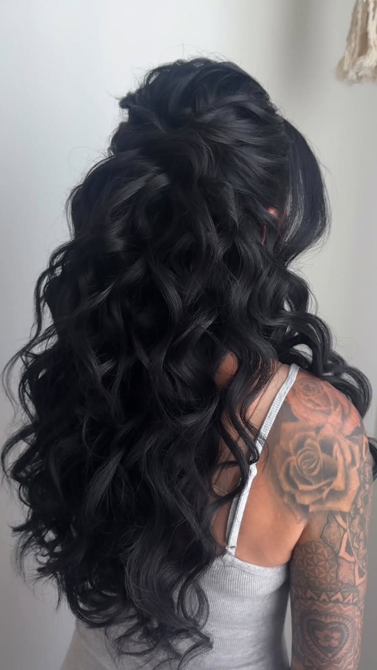 Long black hair styled in a voluminous half-up half-down look with large soft curls.