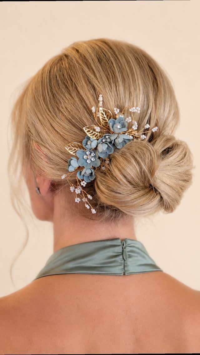 Blonde hair styled in a low bun decorated with blue floral and gold leaf hair accessories.