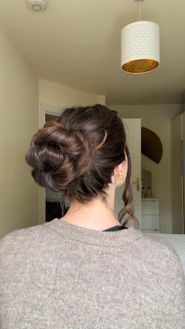 10 Easy Updos for Medium Hair for Wedding Guest Season 2026 9 A woman with dark hair styled in a large, textured artistic bun seen from behind.