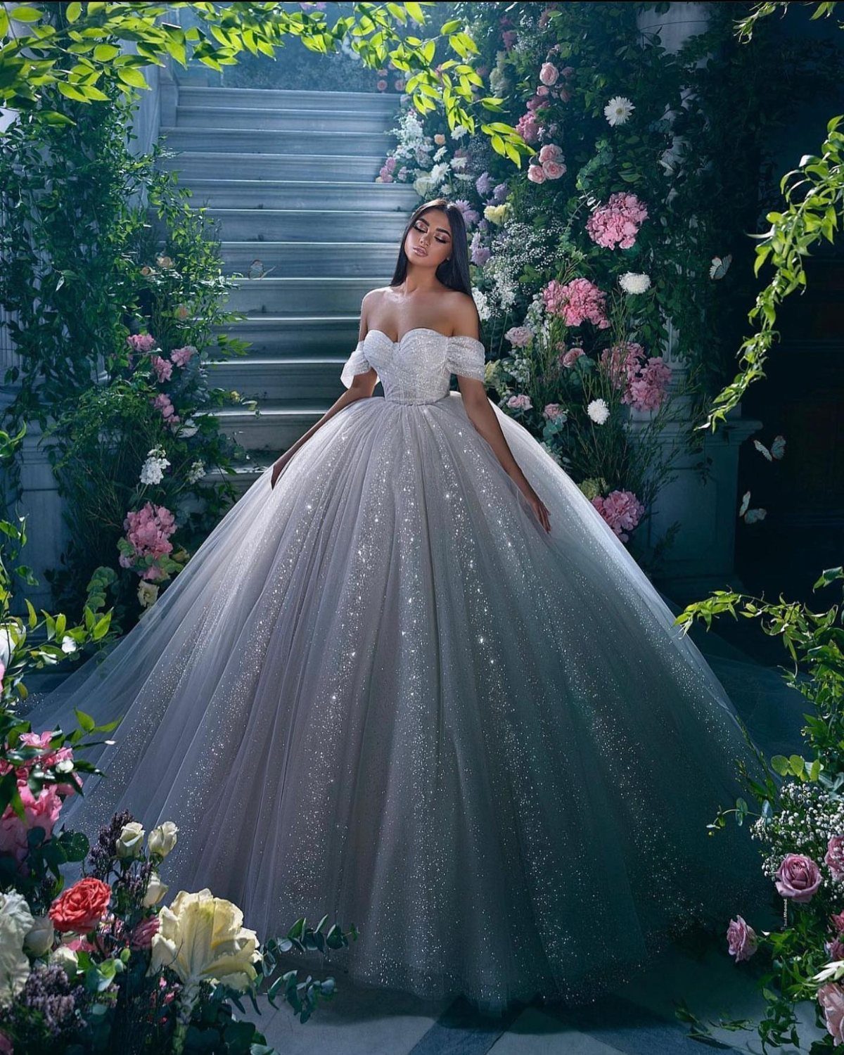 Elegant Princess Wedding Dress Styles in 27 Ideas 18 Woman in a sparkling white ballgown wedding dress standing in a floral garden.