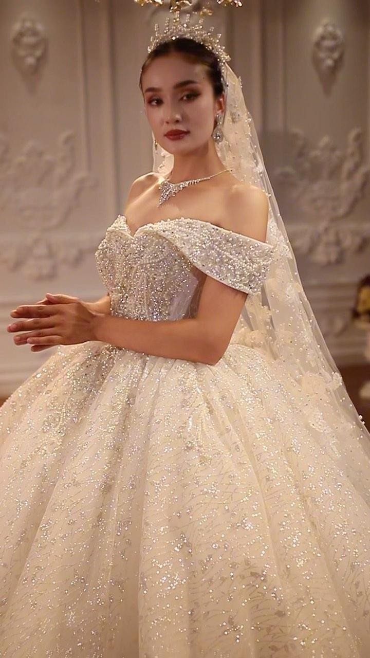 Elegant Princess Wedding Dress Styles in 27 Ideas 5 Woman in a sparkling off-the-shoulder wedding dress with a tiara and long veil.