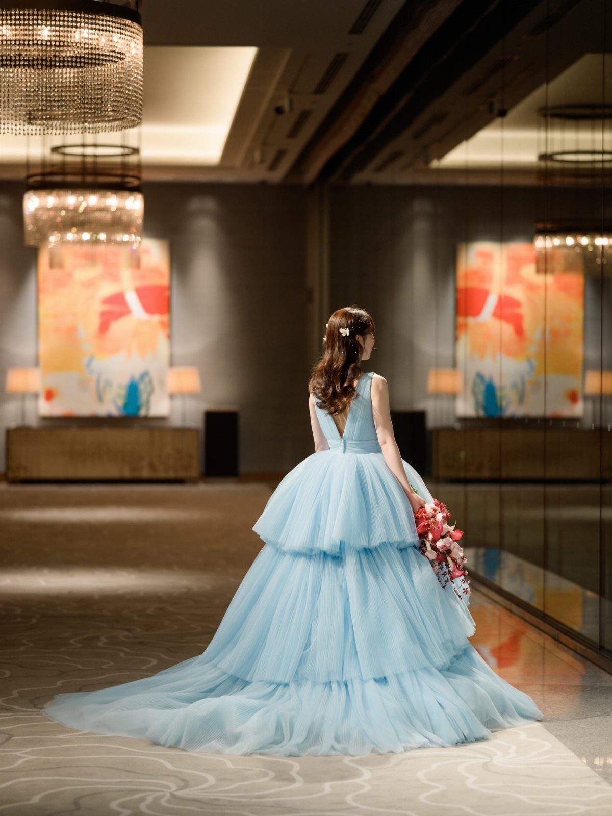 Elegant Princess Wedding Dress Styles in 27 Ideas 3 Woman in a voluminous light blue tiered tulle gown standing in a luxury room.