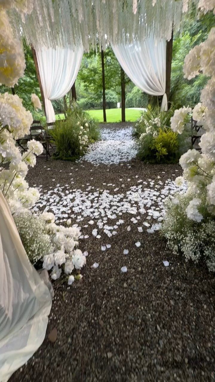 Enchanted Forest Theme Wedding: 12 Ideas for the Ceremony and Reception 12 White flower petals form an aisle between lush white floral arrangements and draped fabric.