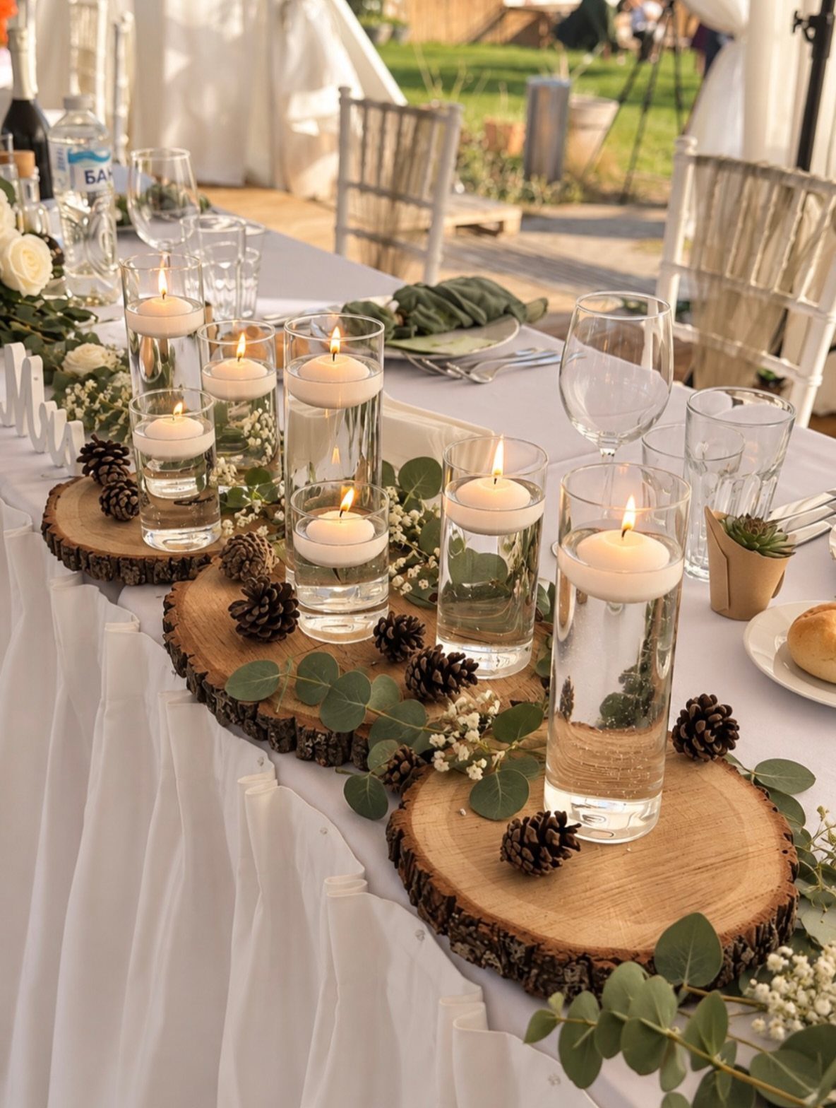 Enchanted Forest Theme Wedding: 12 Ideas for the Ceremony and Reception 10 Wood slice centerpieces with floating candles, pinecones, and eucalyptus leaves on a wedding table.