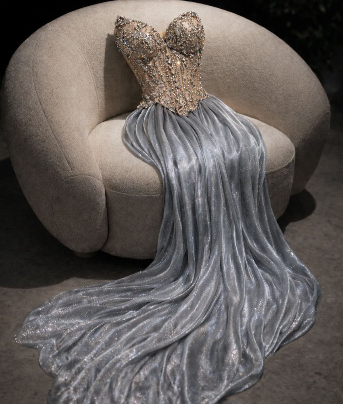 Silver metallic gown with gold embellished bodice draped over a beige armchair