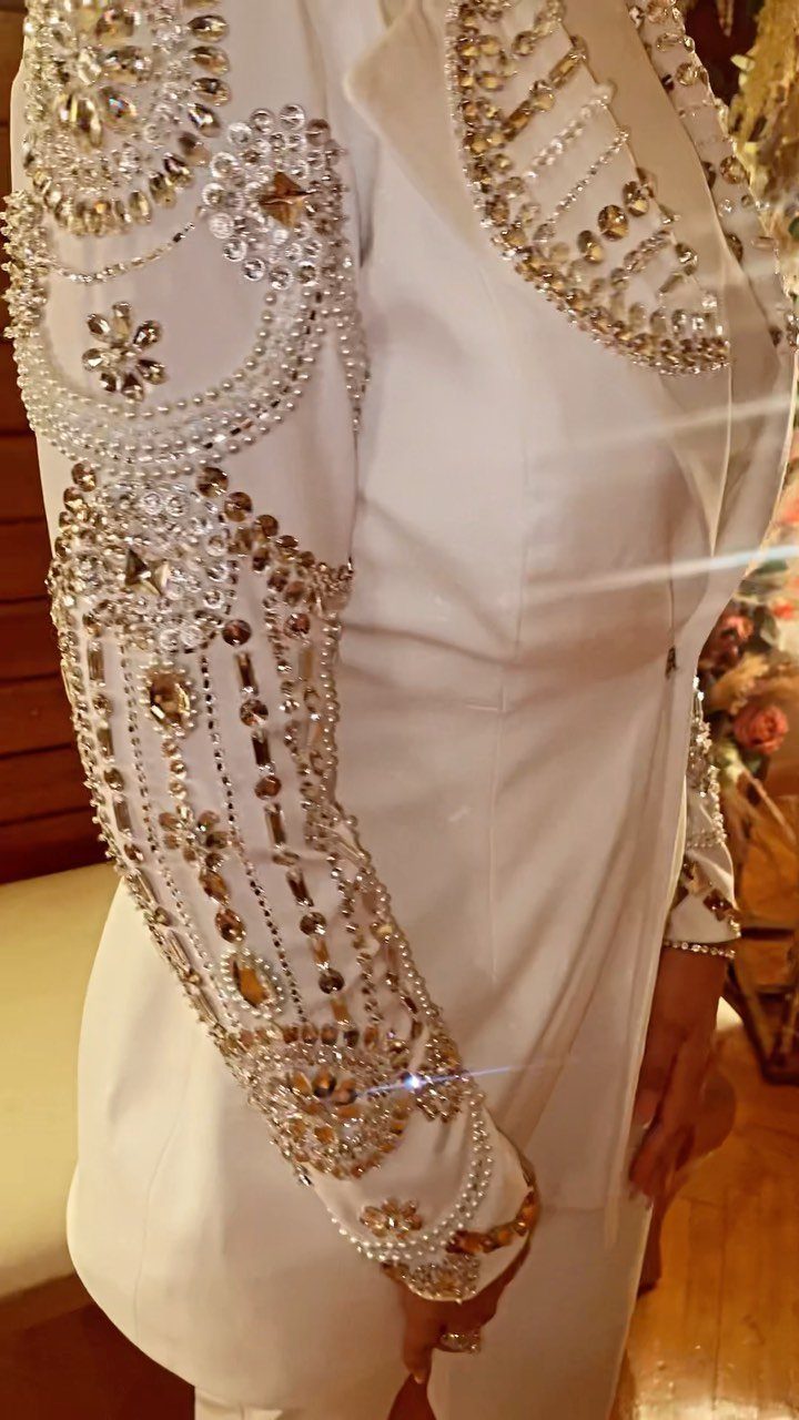 White dress with intricate pearl and crystal embellishments on the sleeve and shoulder.