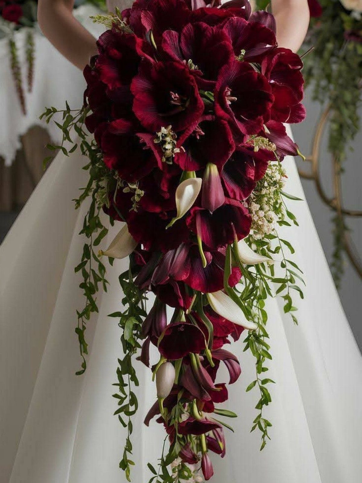 9 Fall Floral Wedding Ideas for Rich Color and Texture 3 A cascading bouquet of deep burgundy calla lilies and green leaves held against a white dress.