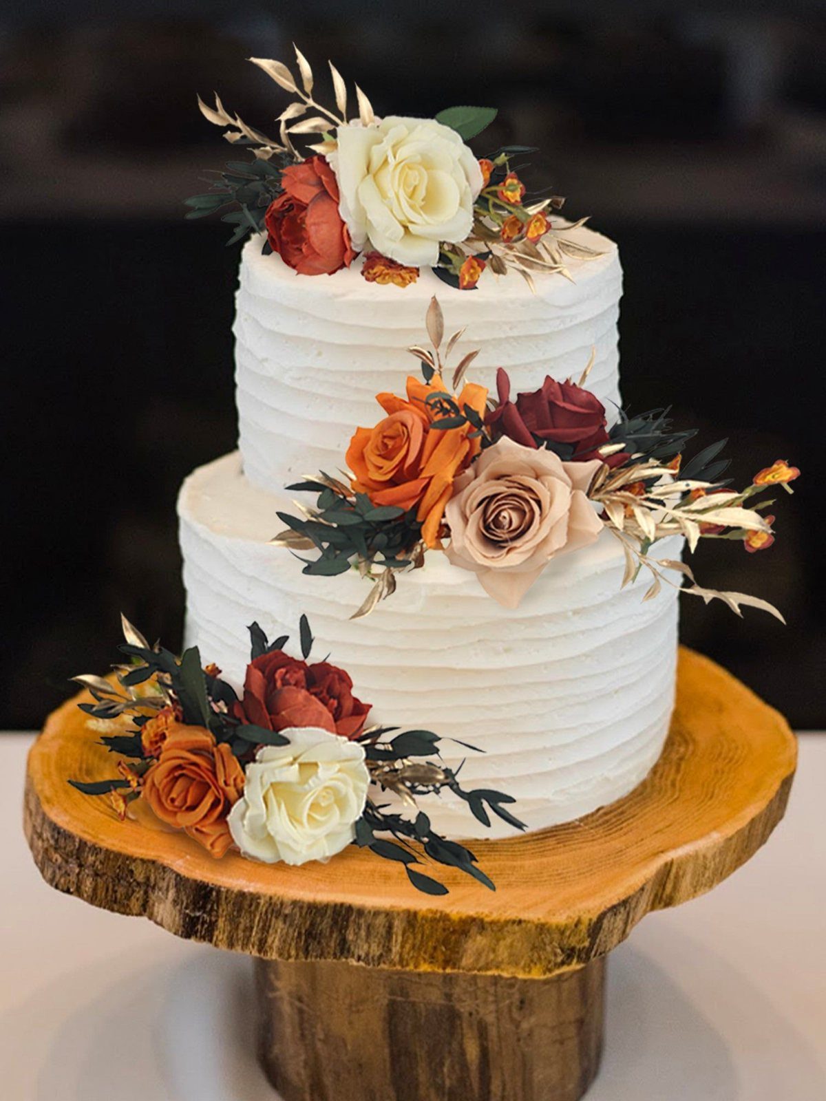 9 Fall Floral Wedding Ideas for Rich Color and Texture 10 Two-tier white wedding cake decorated with roses and gold-painted leaves on a wooden stand.