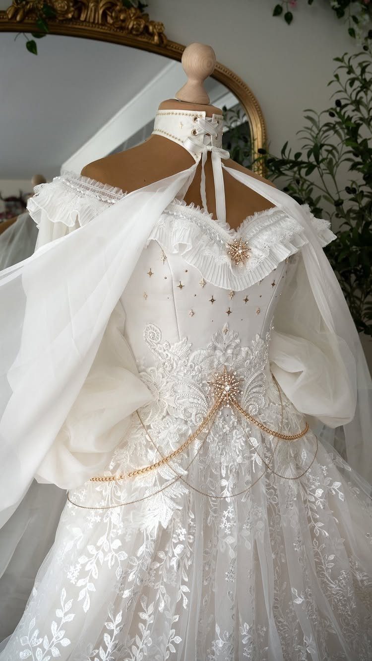 Fantasy Inspired Wedding: 9 Ideas from Forest Photos to Celestial Lace 10 White lace wedding dress with gold chains and ruffled sleeves on a mannequin.