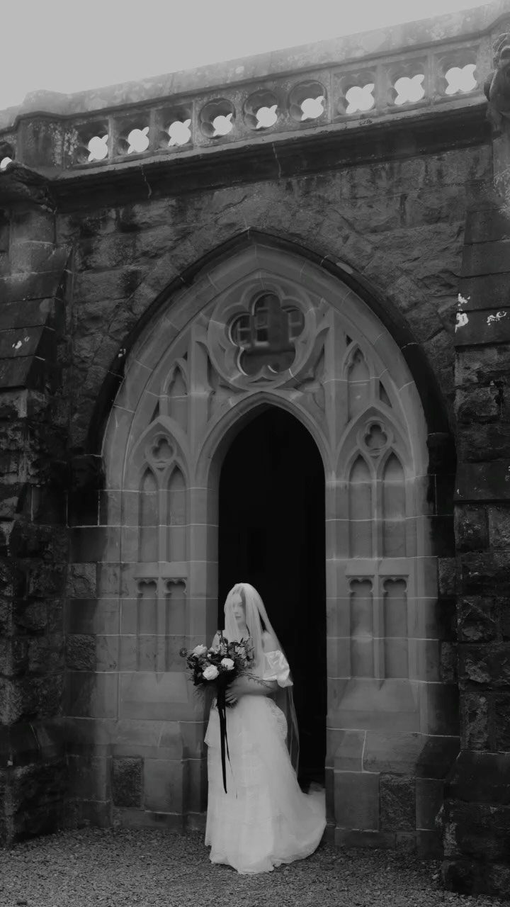 Fantasy Wedding Ideas: 9 Decor, Attire and Theme Details for 2026 6 A bride in a white gown and veil standing in a gothic stone archway.