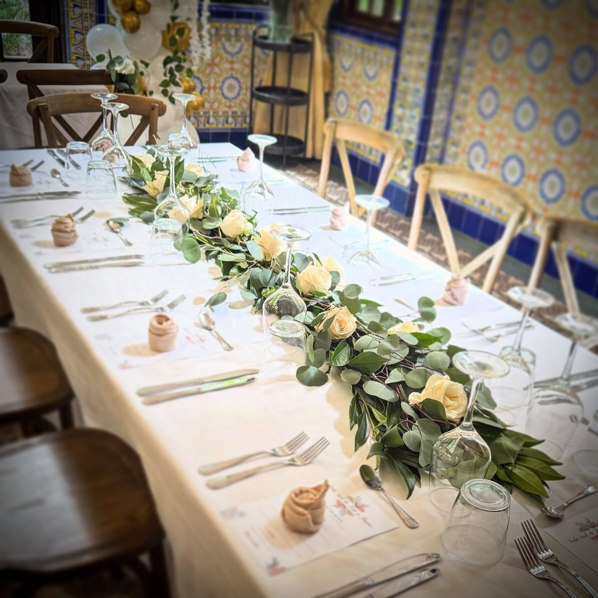 Flower Wedding Decor: 8 Ideas for Ceremony and Reception 5 A long white dining table decorated with a green eucalyptus and rose floral swag runner.