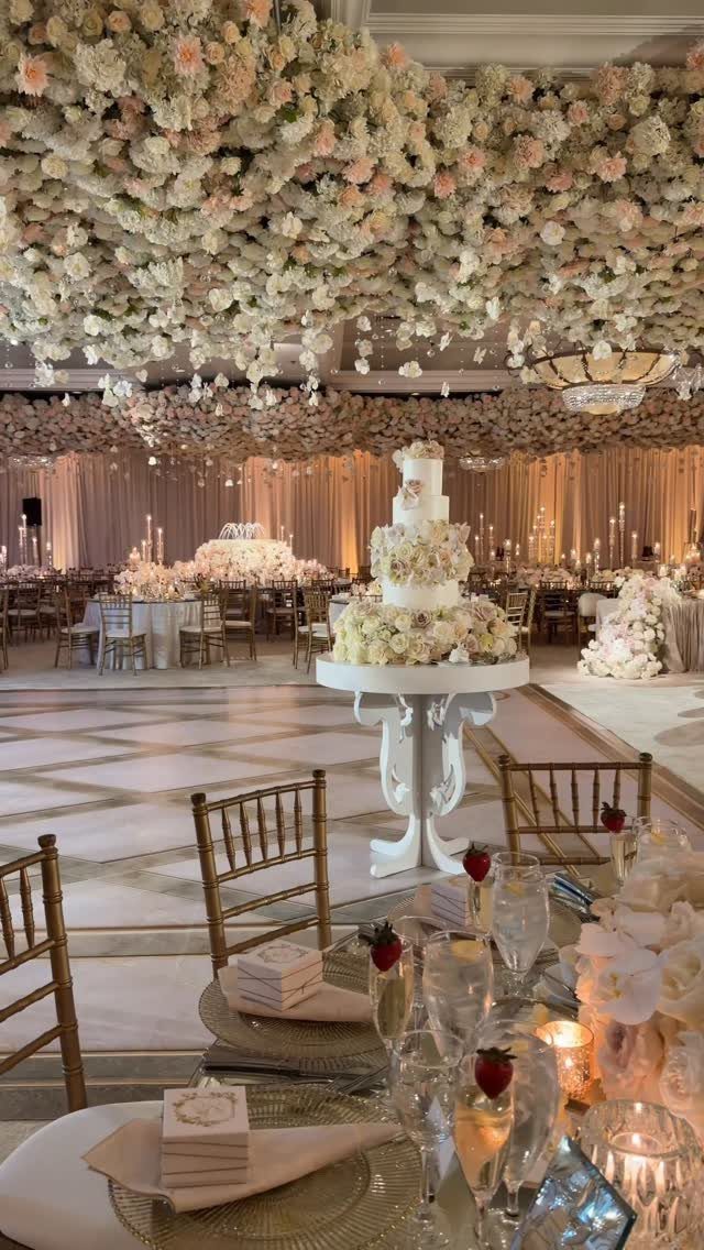 Flowers for Wedding Reception: 11 Elegant Ideas to Style Your Space 2 Wedding reception hall with floral ceiling, white tiered cake, and gold chairs.