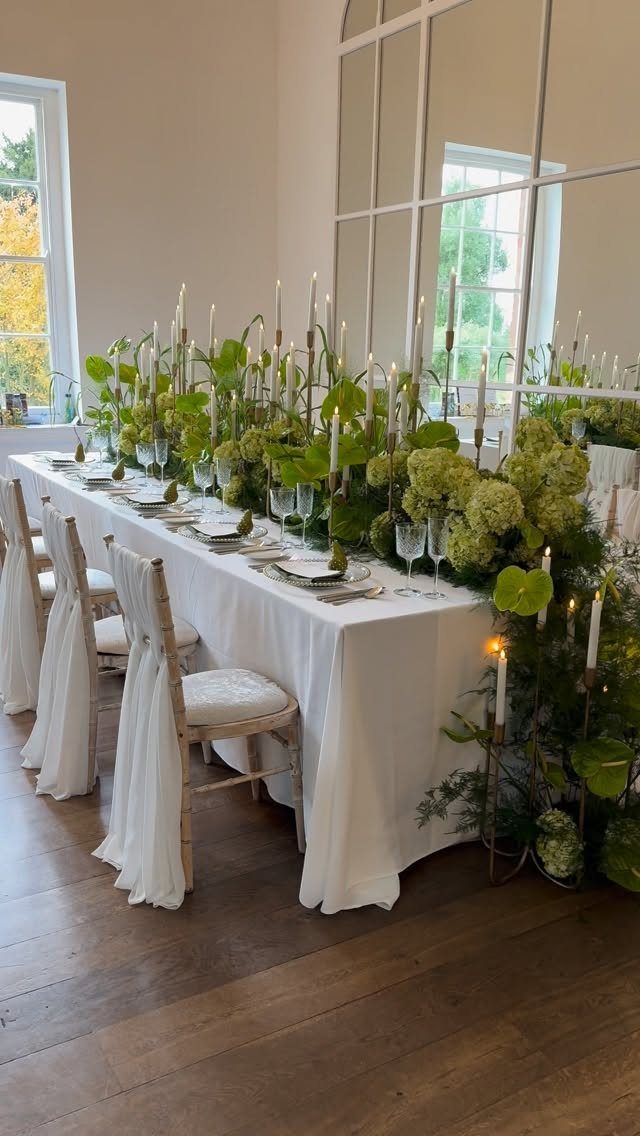 Flowers for Wedding Reception: 11 Elegant Ideas to Style Your Space 8 Long wedding table with white linens, green floral runner, and white taper candles.