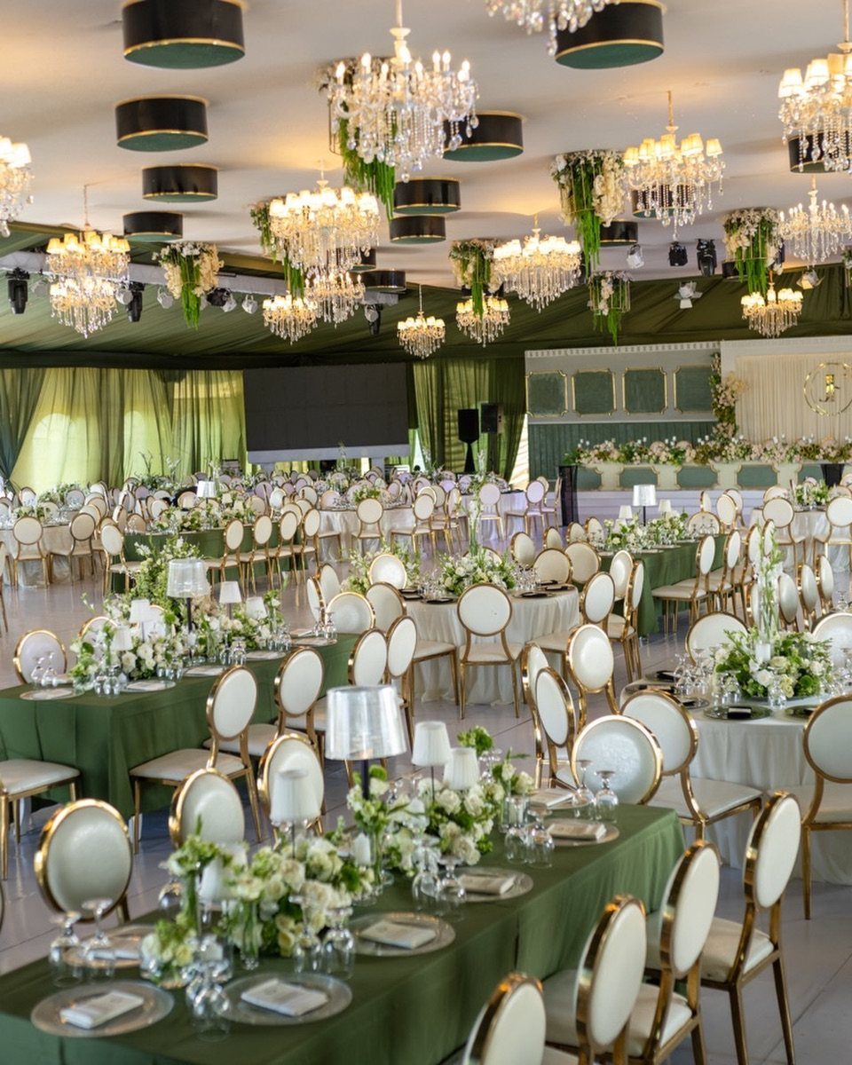 Forest Green for Wedding Colors: 10 Ideas to Try 8 Wedding reception tables with forest green linens, white flowers, and crystal chandeliers in a large hall.