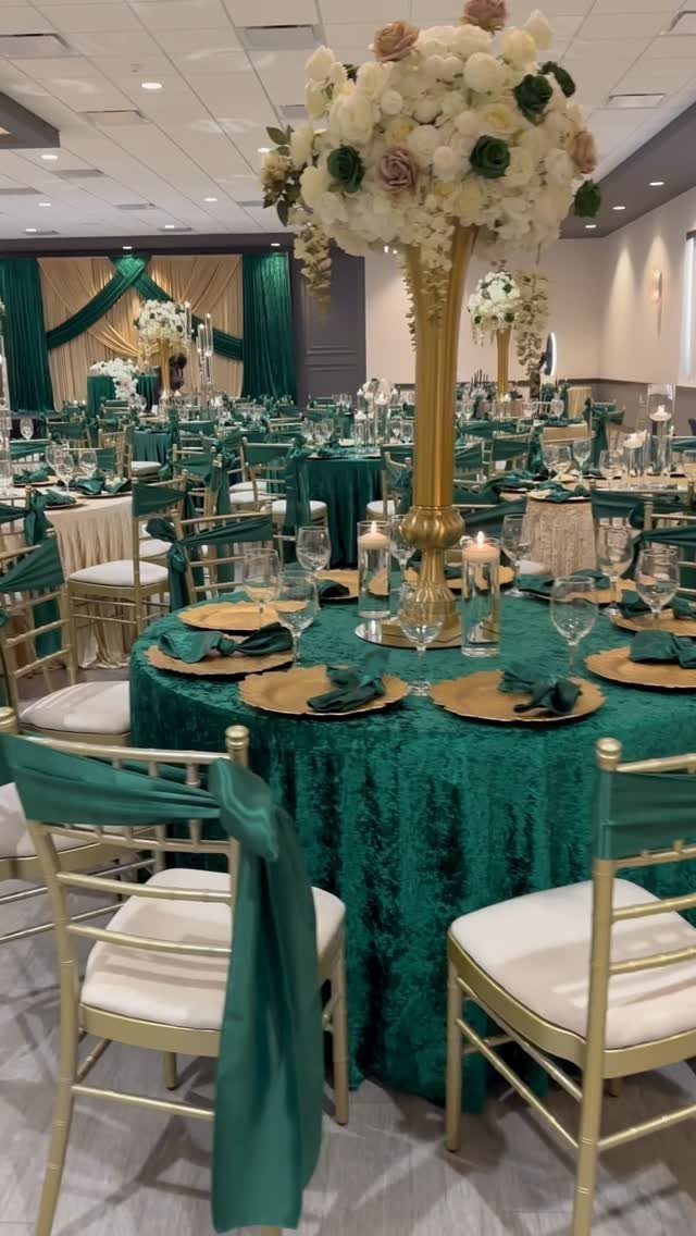 Forest Green for Wedding Colors: 10 Ideas to Try 9 A wedding reception table featuring a forest green tablecloth, gold accents, and a large floral centerpiece.