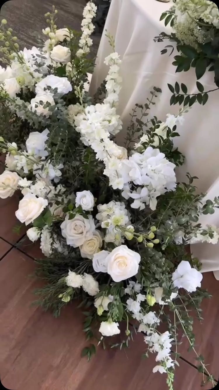Forest Green for Wedding Colors: 10 Ideas to Try 3 White roses and delphiniums with green foliage arranged next to a white tablecloth.