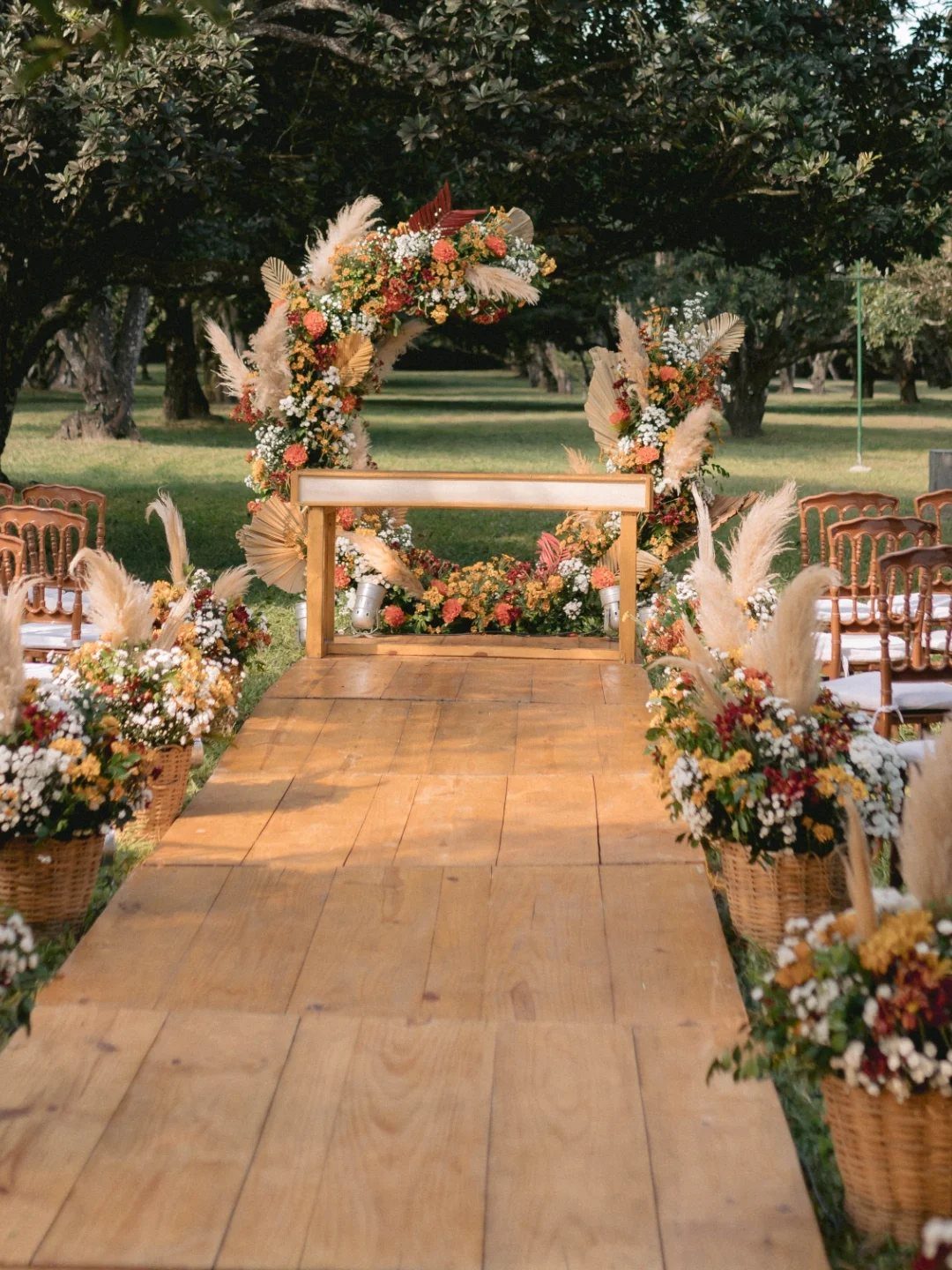 19 Forest Theme Wedding Decorations From Greenery Canopies to Candlelit Paths 20 Wooden wedding aisle lined with floral baskets leading to a decorated altar under trees.