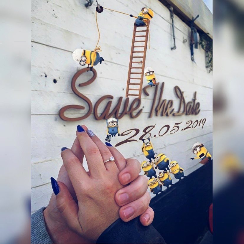 7 Funny Save the Date Ideas That Skip the Boring Part 2 Hands with engagement ring in front of a Save The Date sign with Minions.