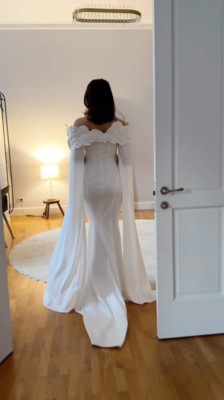 Goddess Wedding Dress Styles: 19 Ideas for 2026 7 Woman from behind wearing a white wedding gown with long cape sleeves.
