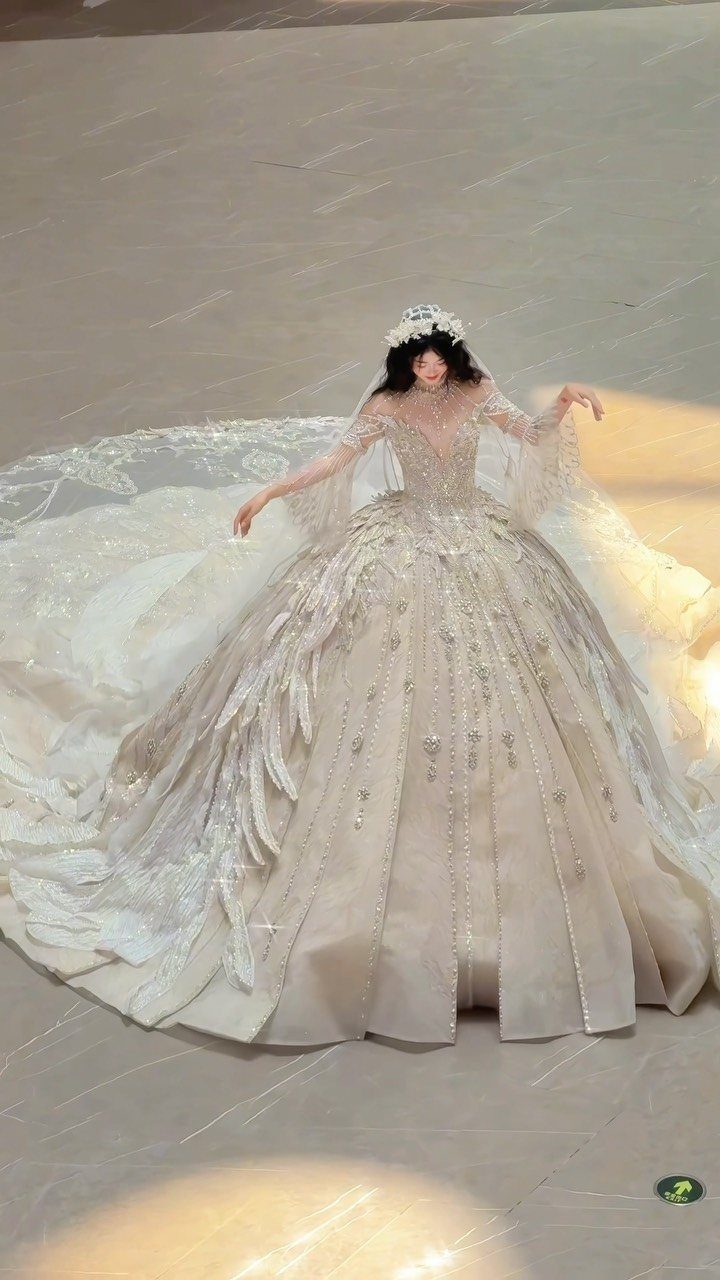 Goddess Wedding Dress Styles: 19 Ideas for 2026 18 Woman in a voluminous cream wedding dress with a floral crown and long train.