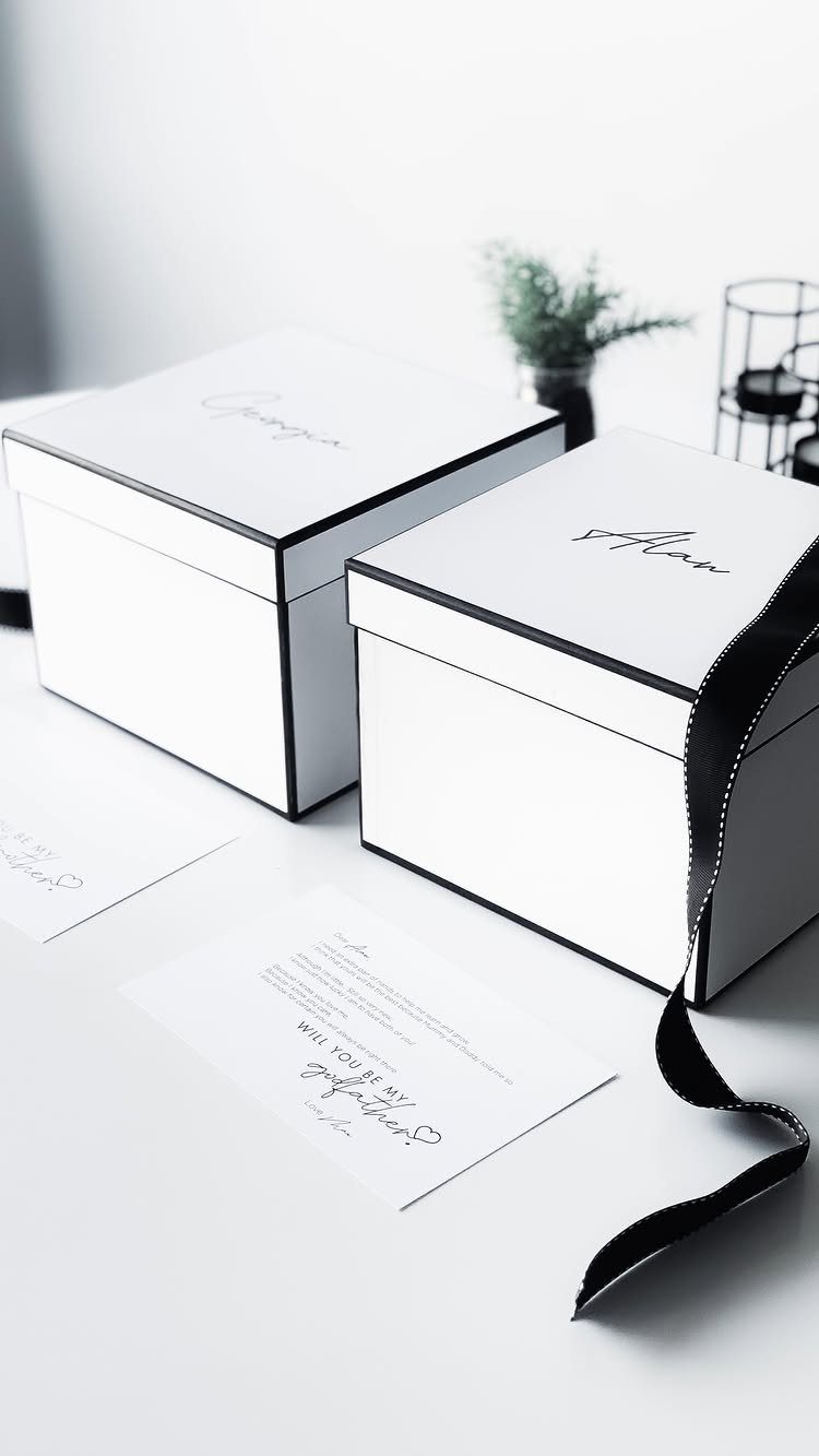 7 Godparent Proposal Box Ideas to Make the Ask Special 6 White gift boxes and a printed godparent proposal card on a white surface.