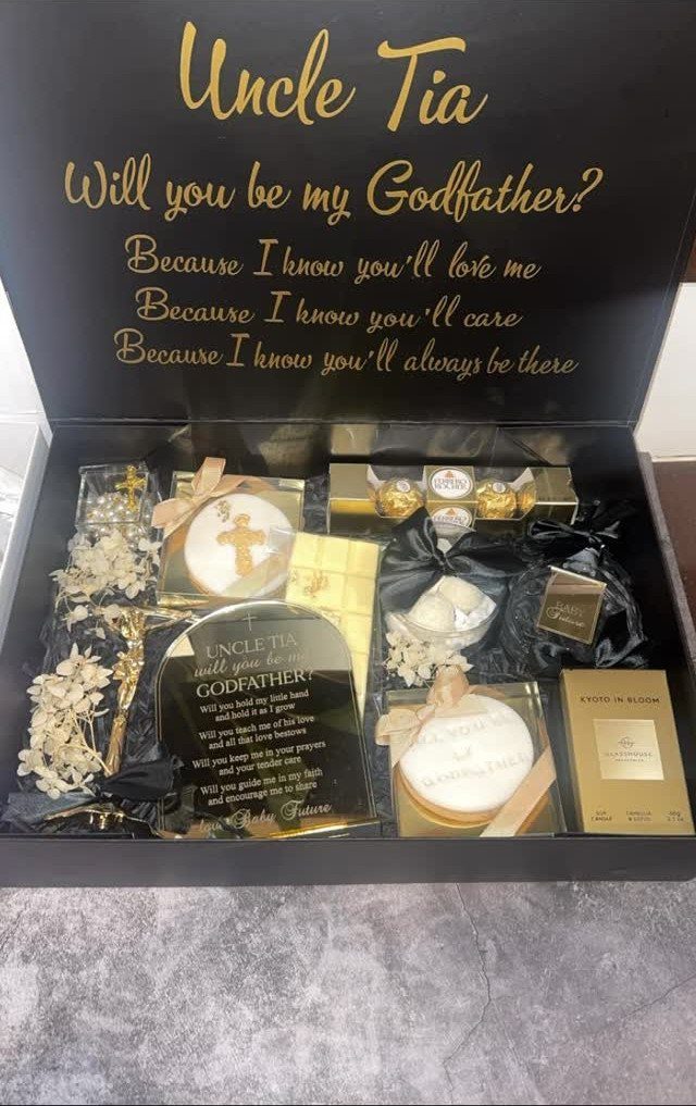 7 Godparent Proposal Box Ideas to Make the Ask Special 7 Black godparent proposal box with gold lettering and various white and gold gifts.